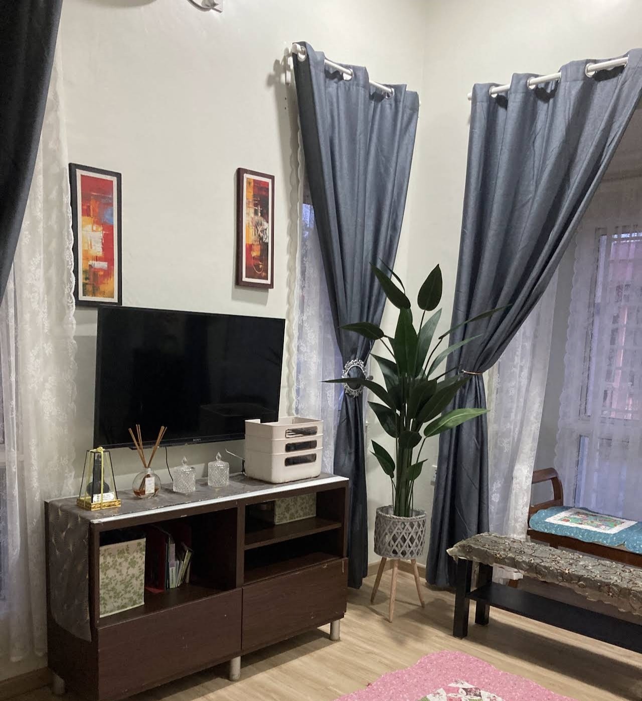 Living room TV console corner with wall art and curtains